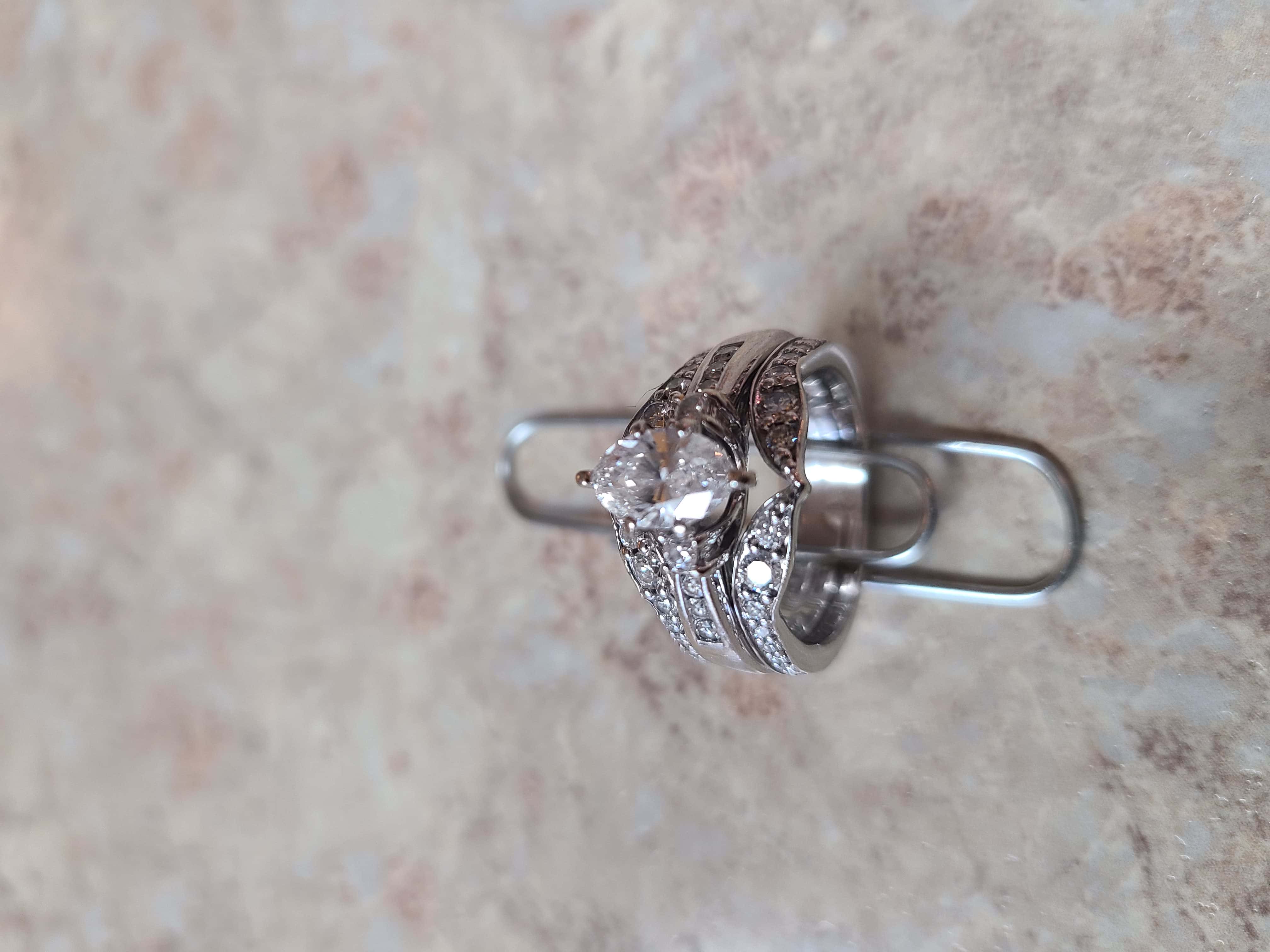 Marquis Shaped Diamond Ring Set in White Gold Held on Paper Clip with Countertop Texture in Background