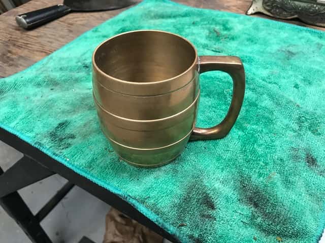 Brass Cup on a Green Towel On an Old Wooden Table