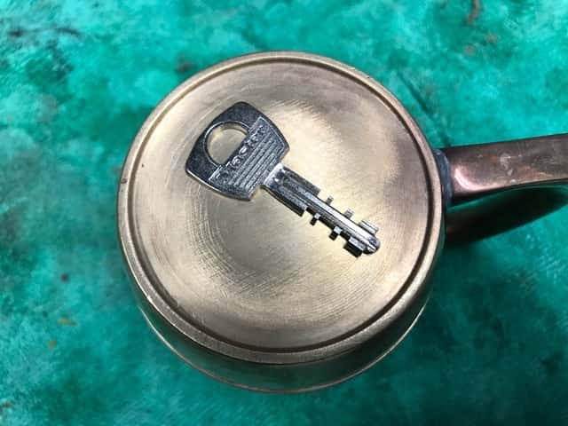 Master Key Resting on Brass Cup  on a Green Towel