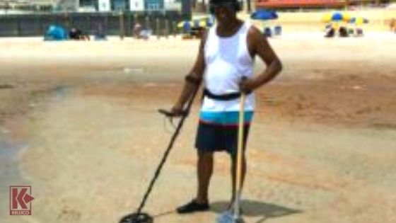 A Man Metal Detects At A Florida Beach With A Metal Detector And A Sand Scoop